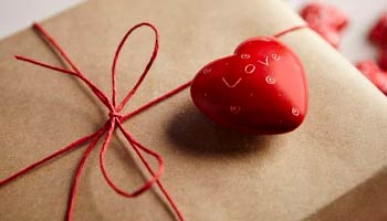 paquete de regalo envuelto con corazón y lazo rojo